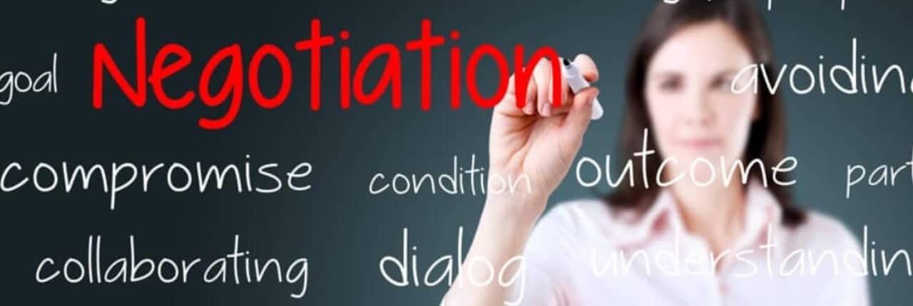 women-glassboard-negotiation-t Woman stands behind a glass marker board and writes Negotiation in red.